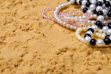 Close up pearl necklaces with copy space. Wet beach sand.