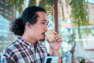 Asian man drinking coffee in a coffee shop
