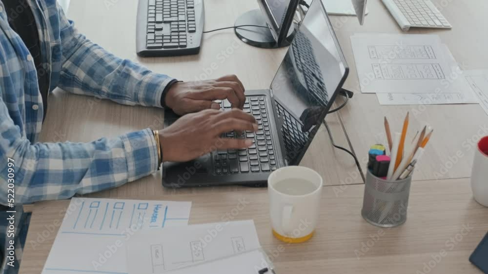Wall mural from above slowmo of unrecognizable male software developer typing on laptop while working in it off