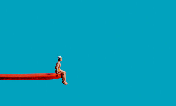miniature man sits on the edge of a diving board