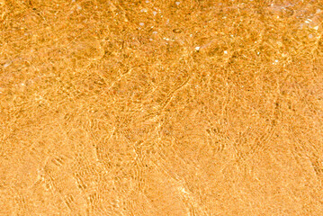 Abstract Transparent and clean yellow water,sand background with sunlight reflection, top view,summer natural day shot.Copy space.
