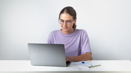 A girl typing at a laptop - remote education and work, online communication