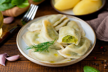 Ukrainian or polish dumplings, pierogi stuffed with potato and spinach mash served with olive oil, closeup view