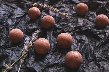 chocolate round candies on black crumpled craft paper with lavender flowers
