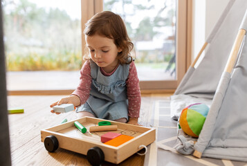 childhood, hygge and people concept - little baby girl playing with toy blocks at home © Syda Productions