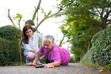 Fototapeta premium Asian senior woman fell down on lying floor because faint and limb weakness and Crying in pain form accident and her daughter came to help support. Concept of old elderly insurance and health care