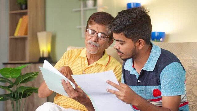 Grandfather with son discussing about education or property documents at home - concept of Medical insurance, financial debt and Mortgage
