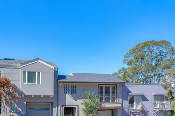 Facade of three houses with gray color scheme exterior against the blue sky in San Francisco, CA