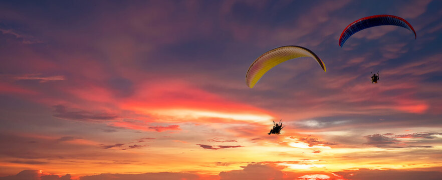 Skydiving sunset landscape of parachutist flying in soft focus. Para-motor flying silhouette with sun set. Silhouette of paraglider flying in the evening sky with sunset.