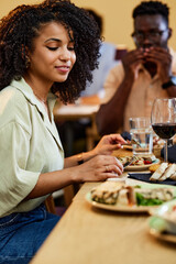 A Hispanic girl enjoys dinner in a restaurant with her friends.