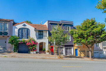 Sloped row of houses in San Francisco, California with trees and plants near the sidewalk