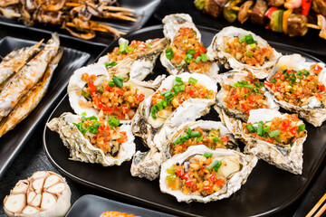 Various barbecue delicacies are placed on the black wood background