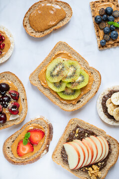 Various kind of open sandwiches with berries and fruits. Made from bread, such as wholegrain, rice crakers, crispbreads and different nut butter, such as peanut, crunchy cashew and almond butter