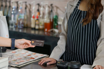 woman customer hand send a credit card to a waitress for pay a coffee drink at counter bar in the coffee shop