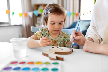 holidays, family and people concept - mother and little baby daughter coloring easter bunny with...