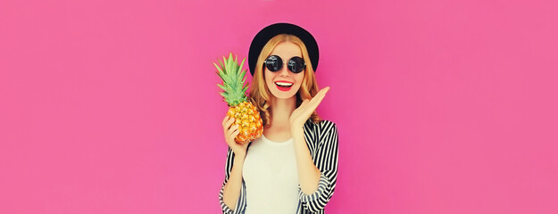 Summer portrait of happy smiling woman with pineapple wearing black round hat, sunglasses on pink...