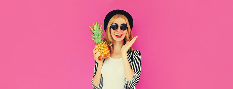 Summer portrait of happy smiling woman with pineapple wearing black round hat, sunglasses on pink background, blank copy space for advertising text
