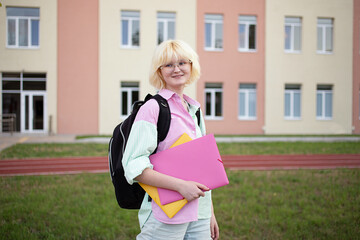 Happy teenage girl with big backpack outdoor,near the nstitution of higher learning.