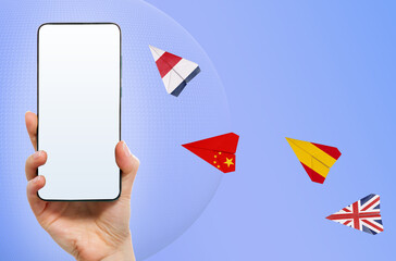 Online education. Female hand holds a smartphone with mock up. Flying paper airplanes with flags of different countries. Concept of learning foreign languages and internet translator