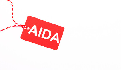 The inscription AIDA Attention Interest Desire Action on a red price tag on a light background. Advertising concept. Copy space