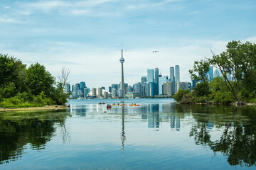 Boaters in canoes and kayaks seen from the Toronto Islands with the city's downtown skyline and an...