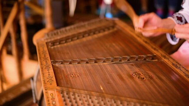 Playing ancient musical instrument. Percon playing with sticks on wooden dulcimer.