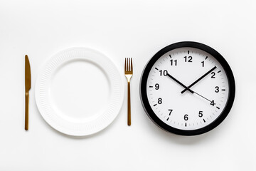Round wall clock with empty plate. Diet or meal time concept