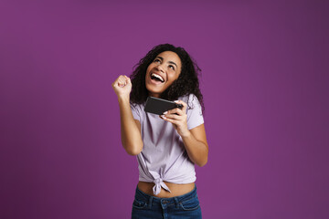 Fototapeta premium Young black woman gesturing while playing online game on cellphone