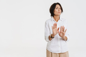 Mature brunette woman frowning while making stop gesture