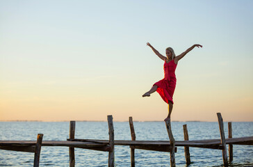 Beautiful young woman posing on jetty at sunset