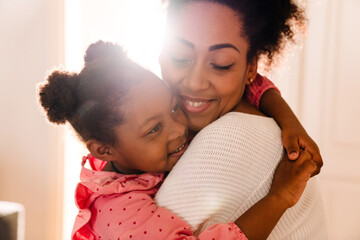 African american happy woman smiling and hugging her daughter at home