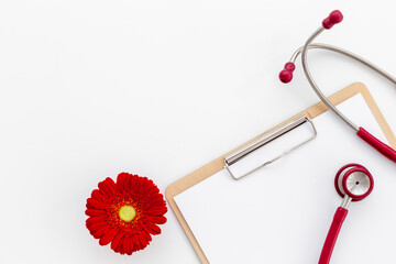 White gynecologist clipboard with red flower and stethoscope