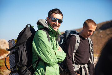 Two men with backpacks hiking in mountainous area. With clipping path - reflection in sunglasses