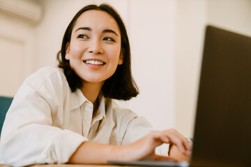 Young cute smiling asian woman with laptop