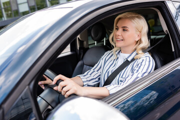 Fototapeta na wymiar Cheerful woman looking away during driving courses in car