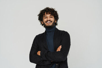Obraz premium Young handsome indian curly smiling man standing arms folded
