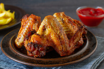 Grilled spicy chicken wings with ketchup on a plate on a table.