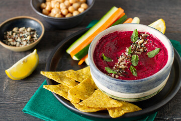 Roasted beet hummus with vegetables in a ceramic bowl on a gray background. 