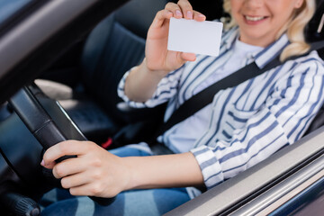 Cropped view of blurred woman holding driving license in car