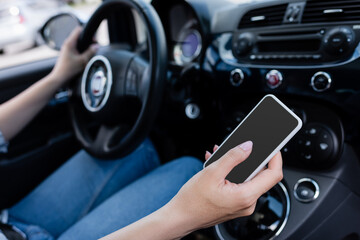 Cropped view of smartphone with blank screen in hand of driver in car