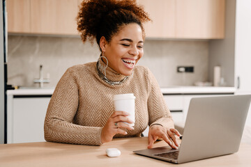 Young beautiful happy smiling african woman with coffee and laptop