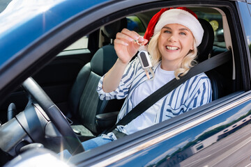 Cheerful driver in santa hat holding key in auto