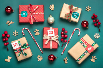 Xmas advent calendar concept Handmade wrapped red, green gift boxes decorated with ribbons, snowflakes and numbers, Christmas decorations and decor on green table Top view Flat lay Holiday card