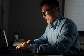 Adult happy man in glasses working with laptop