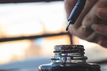 woman filling fountain pen from the inkwell