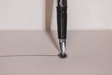 silver fountain pen vertical on a white background making a line
