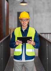architecture, construction business and building concept - happy smiling male architect in helmet and safety west with tablet pc computer at office
