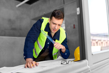 architecture, construction business and people concept - male architect with blueprint and ruler...