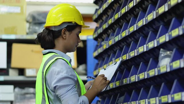Indian woman worker. Happy female factory manager checking order on cardboard in industrial warehouse factory. Portrait Indian women worker working.