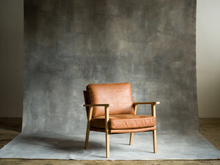 Empty brown leather chair against concrete wall